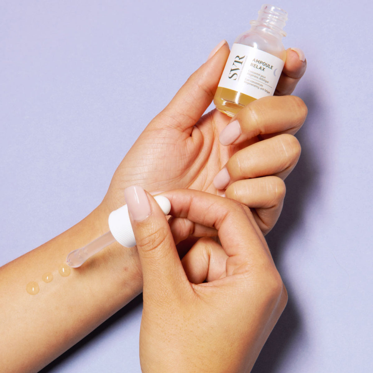 Dłoń trzymająca szklaną buteleczkę serum SVR Ampoule Relax i aplikująca kroplę żelowego preparatu za pomocą pipety.