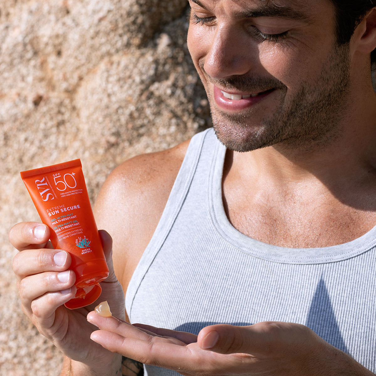 Mężczyzna trzymający pomarańczową tubkę żelu ochronnego SVR SUN SECURE Extreme SPF50+ z transparentną konsystencją na dłoni.