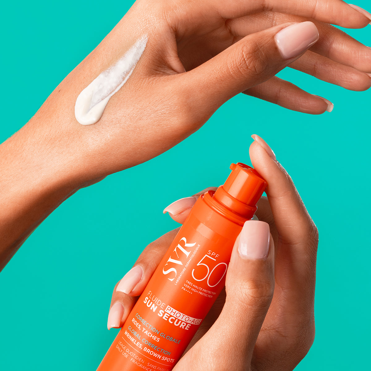 Hands holding an orange SVR SUN SECURE SPF50+ pump bottle with white sunscreen cream applied to the skin.